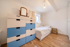 A bedroom with a bed, a dresser, a window with curtains, and a wooden floor. - Wood burner, two lounges and a large garden for up to 8 guests (South Hiendley)