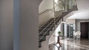 Een modern interieur met een trap, een ronde tafel met een plant en een deur met een ruit.