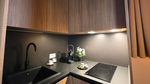 A modern kitchen with a black sink, a coffee maker, a small potted plant, and an induction cooktop. - 111 Isolde Deluxe Room (Palermo)