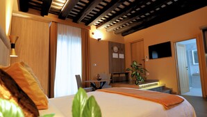 A hotel room with a bed, a desk, a chair, a potted plant, and a television. - 111 Isolde Deluxe Room (Palermo)