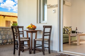 A patio with a table and chairs, a fruit bowl, and a "WELCOME" sign. - Levanta Cozy Apartments in Kalavarda Rhodes (Rhodes)