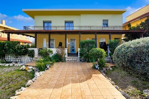 A two-story building with a yellow facade, a balcony, and a tiled entrance area. - Levanta Cozy Apartments in Kalavarda Rhodes (Rhodes)