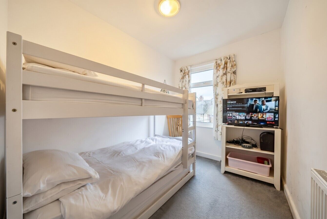 Habitación con literas, televisión y unidad de almacenamiento.