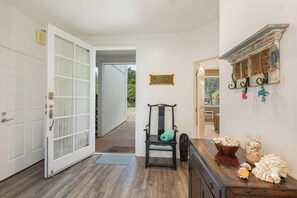 A hallway with a white door, a wooden bench with a cushion, a decorative wall shelf, and a small rug. - Located on Makai Golf Course - Emmalani Court 314 (Princeville)