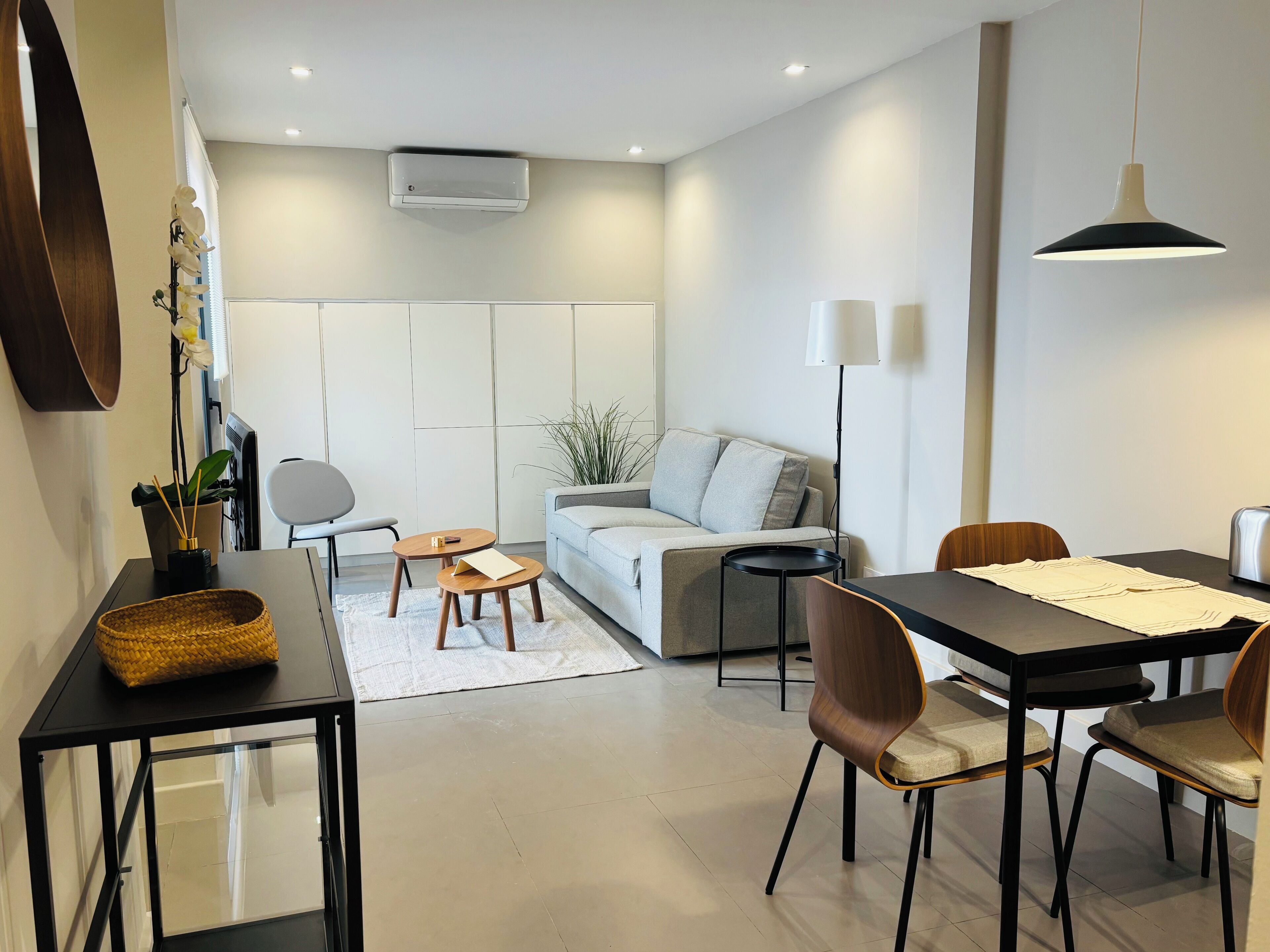 Una sala de estar moderna con sofá, mesa de centro, sillas y mesa de comedor.