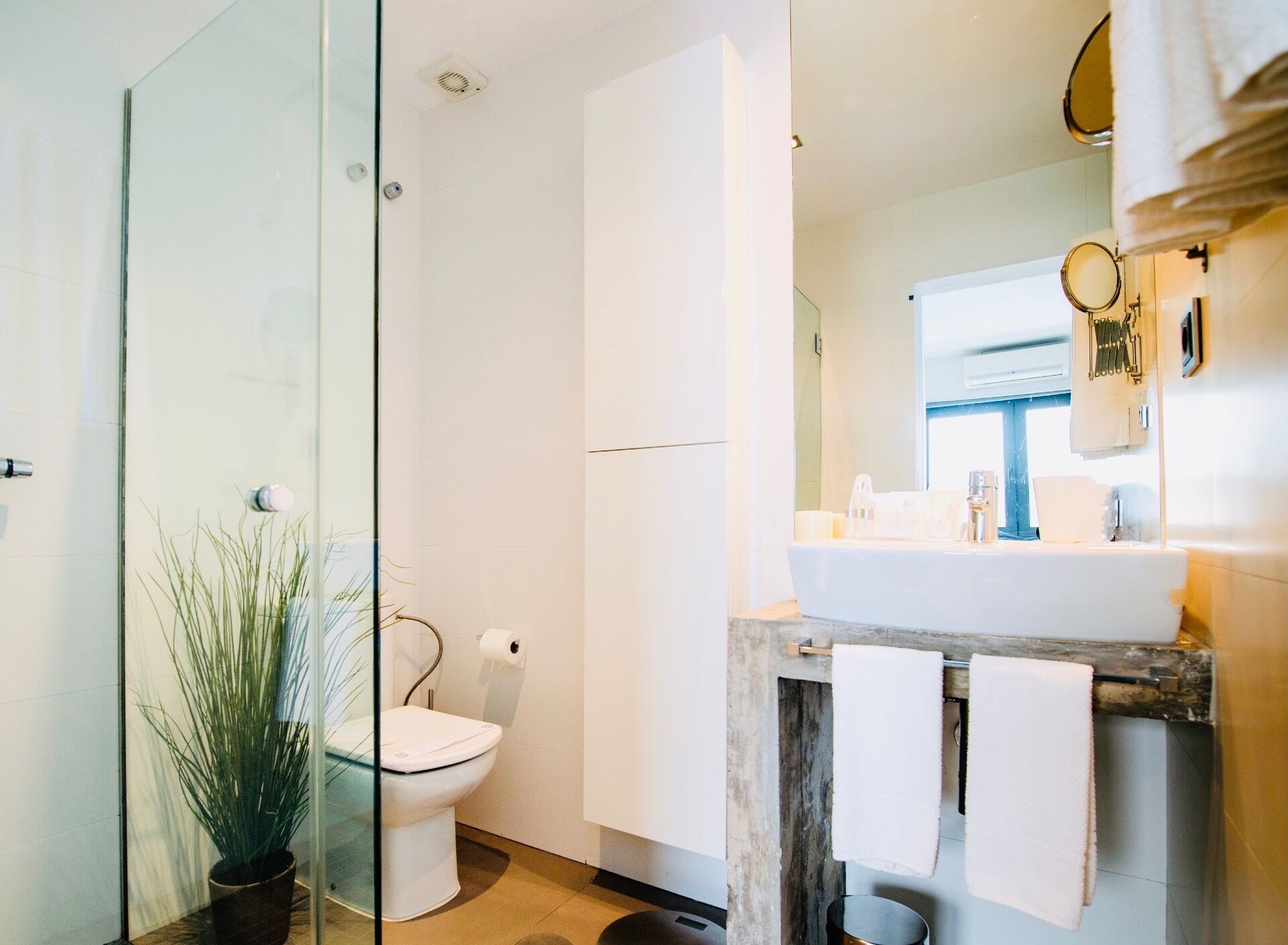 A modern bathroom with a glass shower enclosure, a toilet, a sink with a mirror, and a towel rack.
