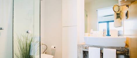 A modern bathroom with a glass shower enclosure, a toilet, a sink with a mirror, and a towel rack.
