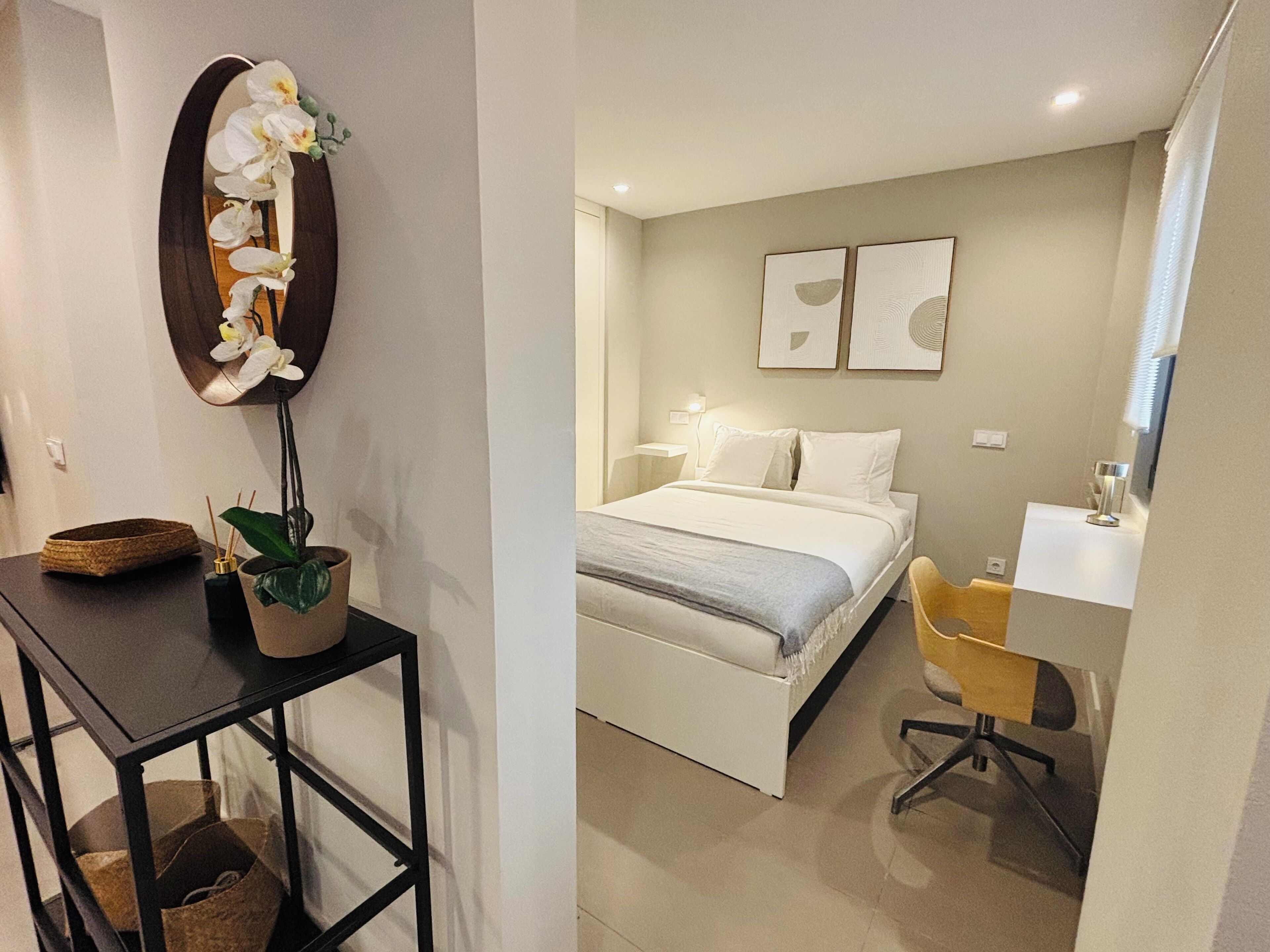 Ein Schlafzimmer mit Bett, Nachttisch, Stuhl und Wandbild.
