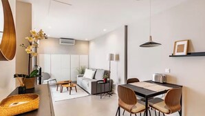 Ein modernes Wohnzimmer mit einer Couch, einem Couchtisch und einem Essbereich mit Stühlen.