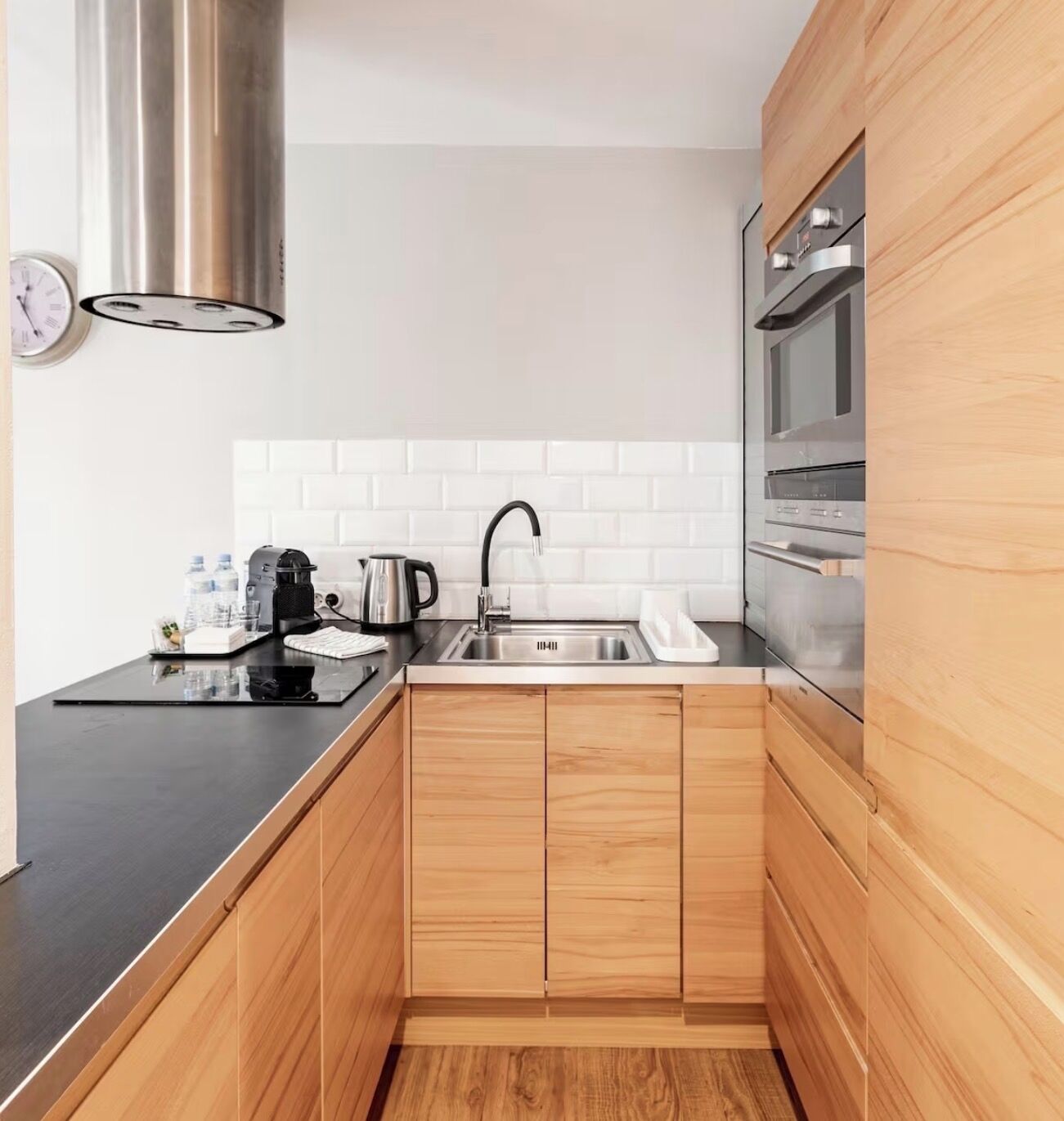 A compact kitchen with a stainless steel sink, a coffee machine, and a kettle on the countertop.