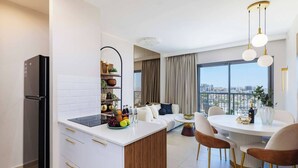 Een moderne keuken met een inbouwkoelkast, witte keukenkastjes en een centraal eiland met fruit.