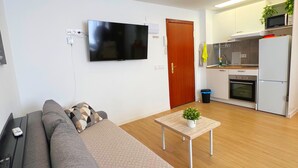 Una sala de estar moderna con un sofá gris grande, una mesa de centro con una planta y un televisor de pantalla plana montado en la pared.