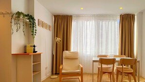 Una sala de estar moderna con comedor, piso de madera, un sofá, una mesa de centro y una planta en maceta.