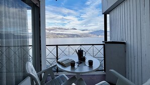 Ein Balkon mit Tisch, Stühlen und Blick auf einen See und Berge.