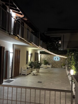 Un patio con mobiliario exterior, plantas en macetas y un muro decorativo.