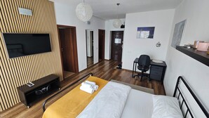 Una habitación de hotel moderna con cama, escritorio, televisión y armario.