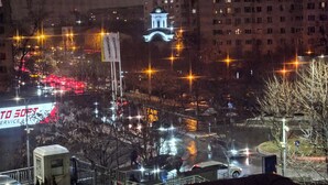 Panorama nocturno de una ciudad con un puente, edificios iluminados y un cartel llamativo que dice 'TO 30FT SERVICE AUTO'.