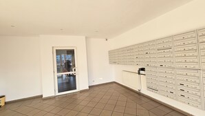 Una habitación con un amplio panel de buzones, una puerta y suelo de baldosas.