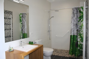Ein Badezimmer mit Dusche, Toilette, Waschbecken und Spiegel.