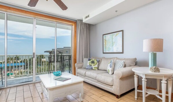 A modern living room with a balcony, a sofa, a coffee table, and a lamp. - Beach Club 136: 1  BR, 1  BA Condominium in Tybee Island, Sleeps 4 (Tybee Island)