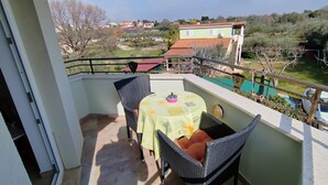 A balcony with a table and chairs, a view of a residential area, and a railing. - Apartments Lighthouse (Fazana)