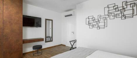 Une chambre moderne avec une armoire en bois, un lit, un bureau et une œuvre d’art murale.