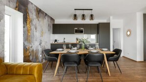 A modern dining area with a wooden table set for four, surrounded by black chairs. - Apartments Villa Wood (Ivanic-Grad)