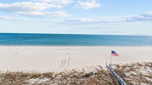 Una playa con arena, una bandera y una valla.