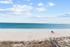 A beach with a sandy shore, a flag, and a fence. - San Carlos 703 by Liquid Life (Gulf Shores)