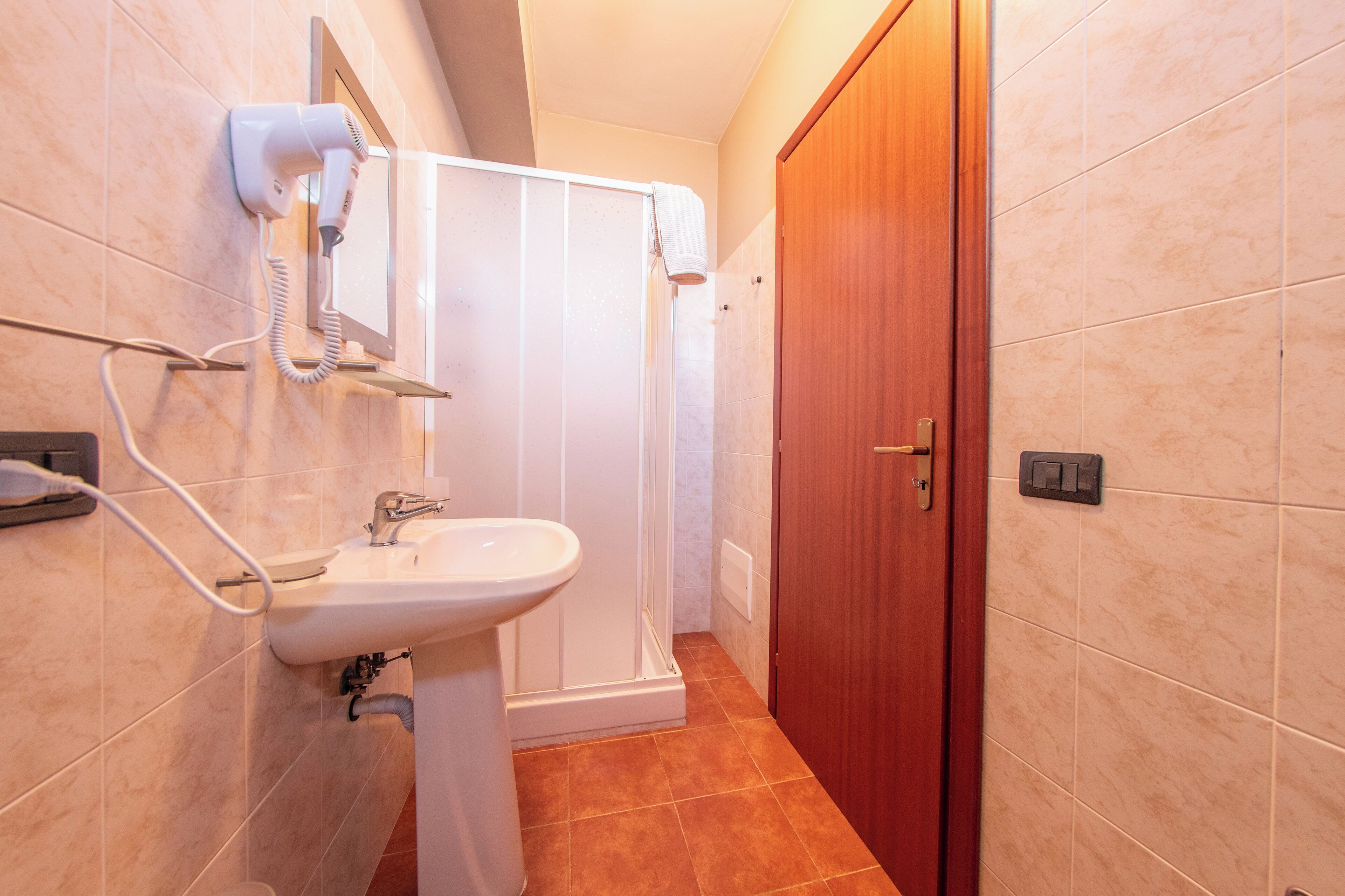 A bathroom with a sink, a hairdryer, and a shower.