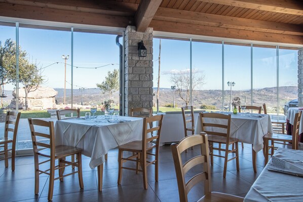 A restaurant with outdoor seating, stone pillars, and a view of the countryside. - Tenuta Giave (Montemarano)