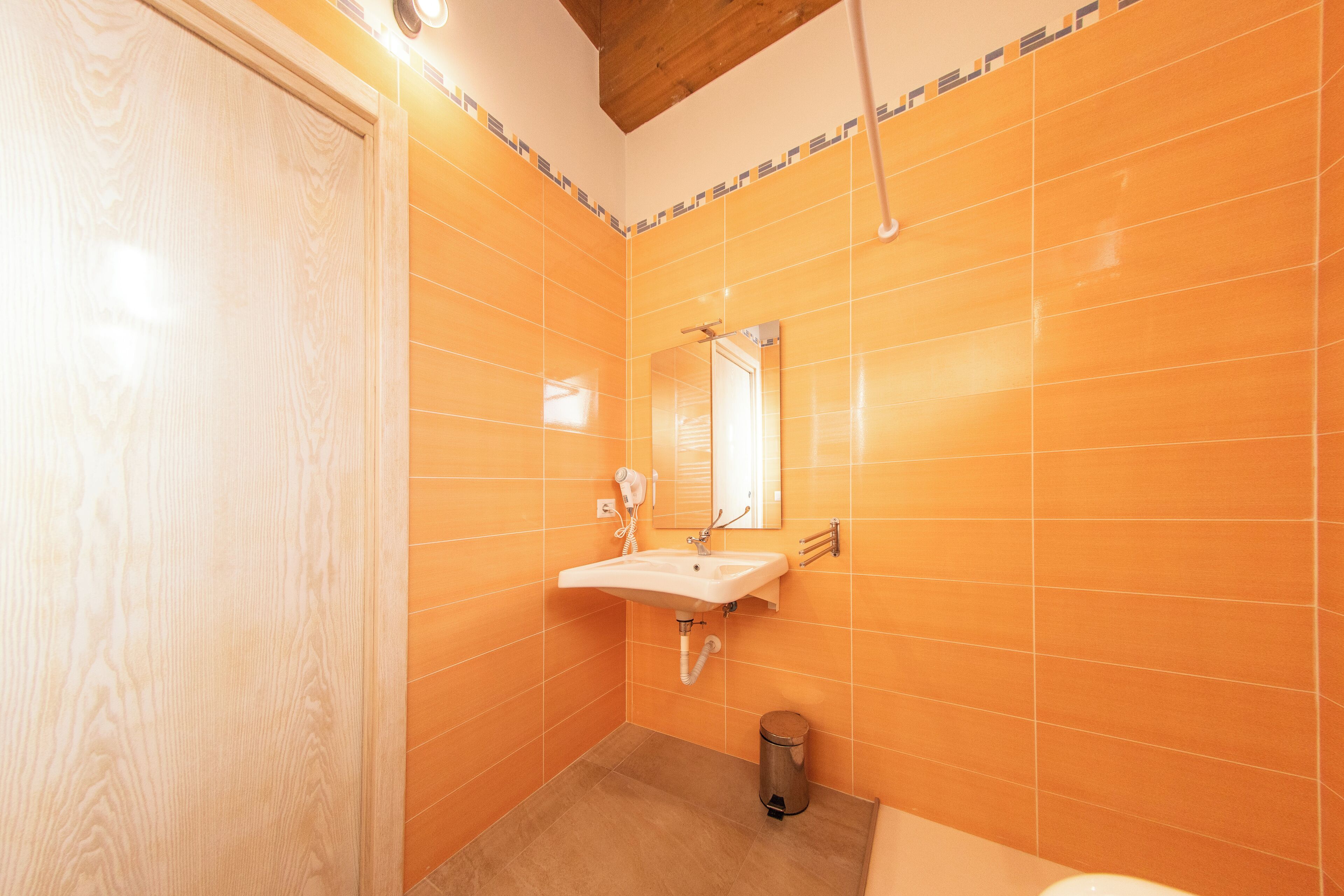 Een badkamer met oranje tegels, een wastafel, een spiegel en een toilet.