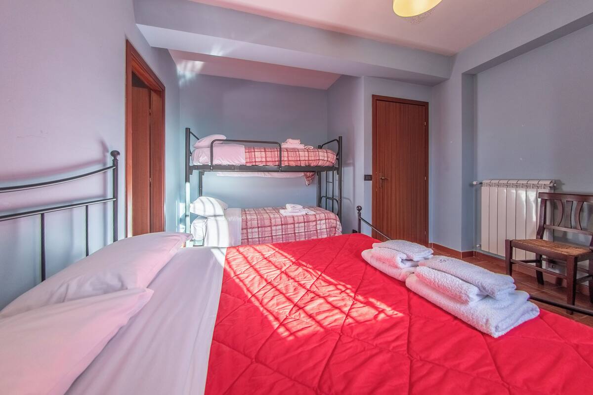 Une chambre avec un lit superposé, un lit simple et une chaise.