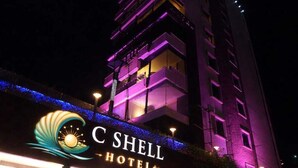A hotel with a prominent sign reading "C Shell Hotel" and a modern design with purple lighting.