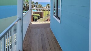 Een overdekt houten terras met uitzicht op de oceaan en een zwembad.