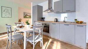 A modern kitchen with white cabinets, a built-in oven, and a coffee maker. - Apartments Zanet & Niccolo (Fazana)