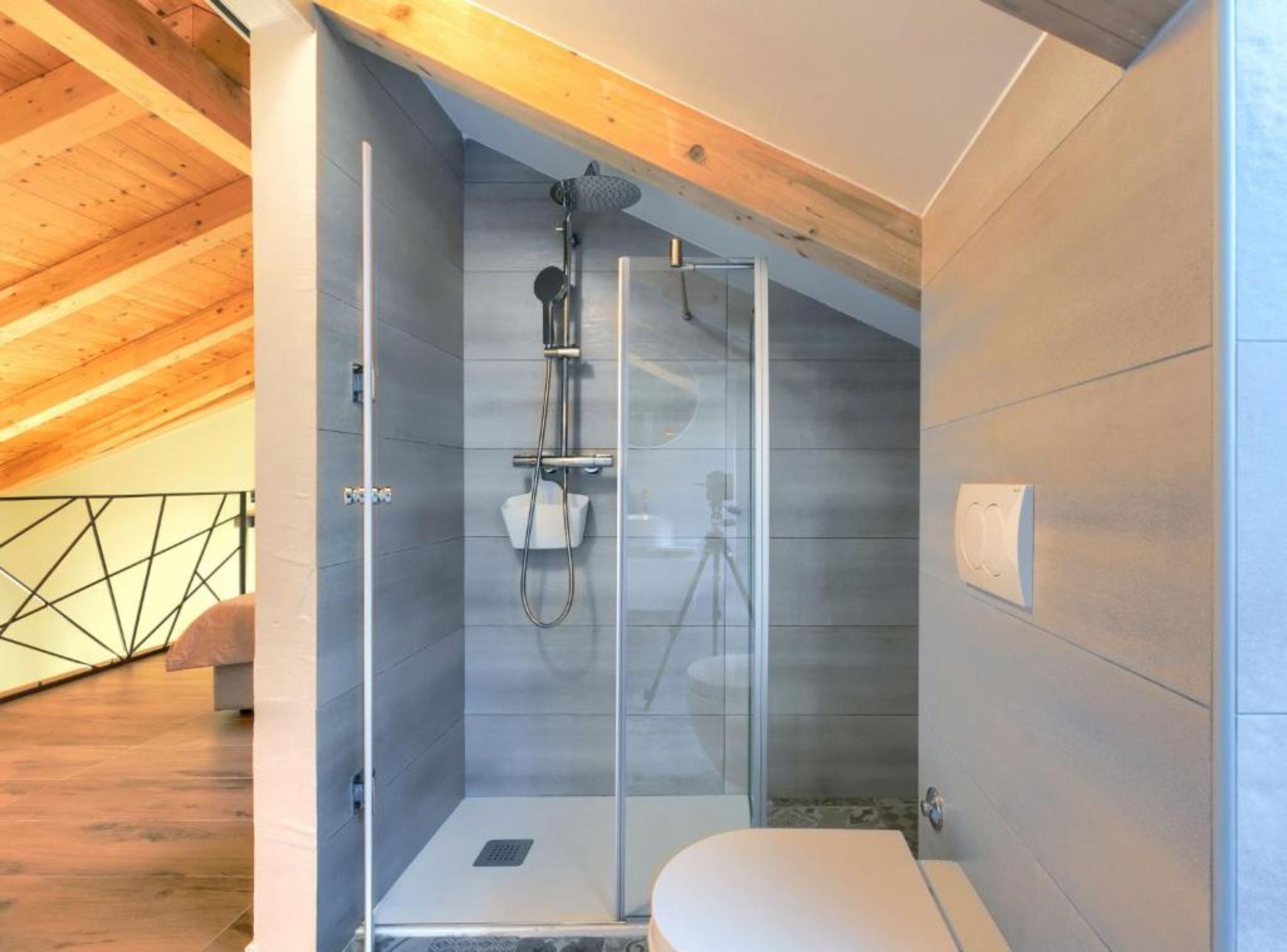 A modern shower room with a glass enclosure, a white toilet, and a wooden ceiling.