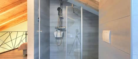 A modern shower room with a glass enclosure, a white toilet, and a wooden ceiling.
