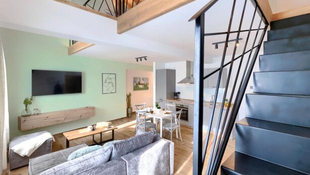 A modern living space with a staircase, a dining area, and a kitchen. - Apartments Zanet & Niccolo (Fazana)