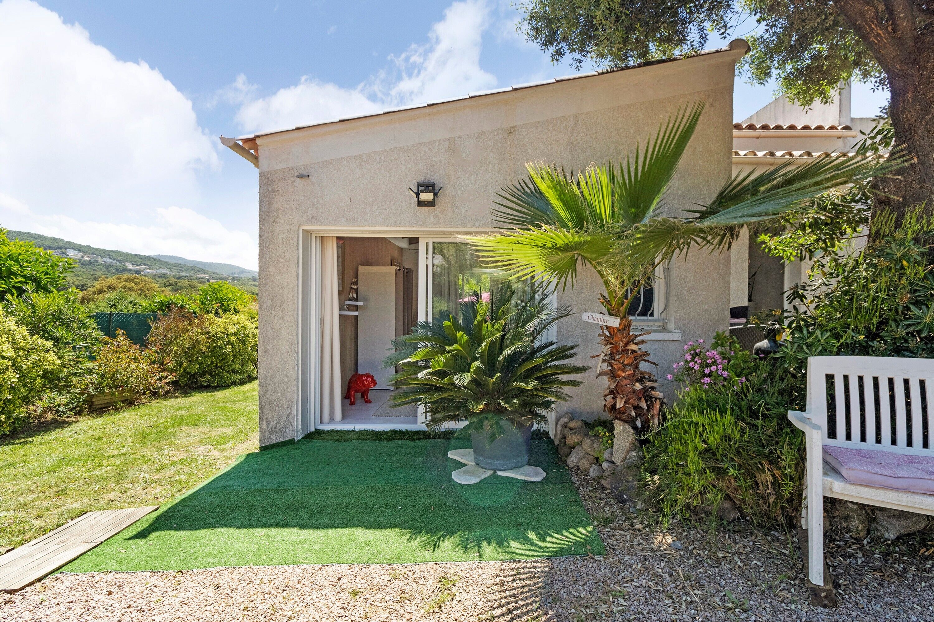 A house with a patio, a bench, and a palm tree.