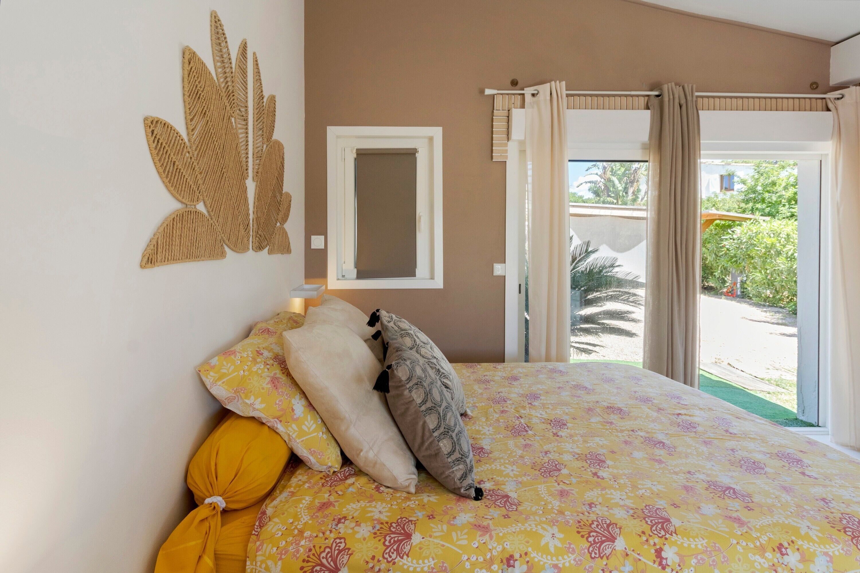Un dormitorio con cama, almohadas, una ventana y vistas al exterior.