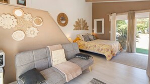 Um quarto com cama, sofá, parede decorada e janela com cortinas.