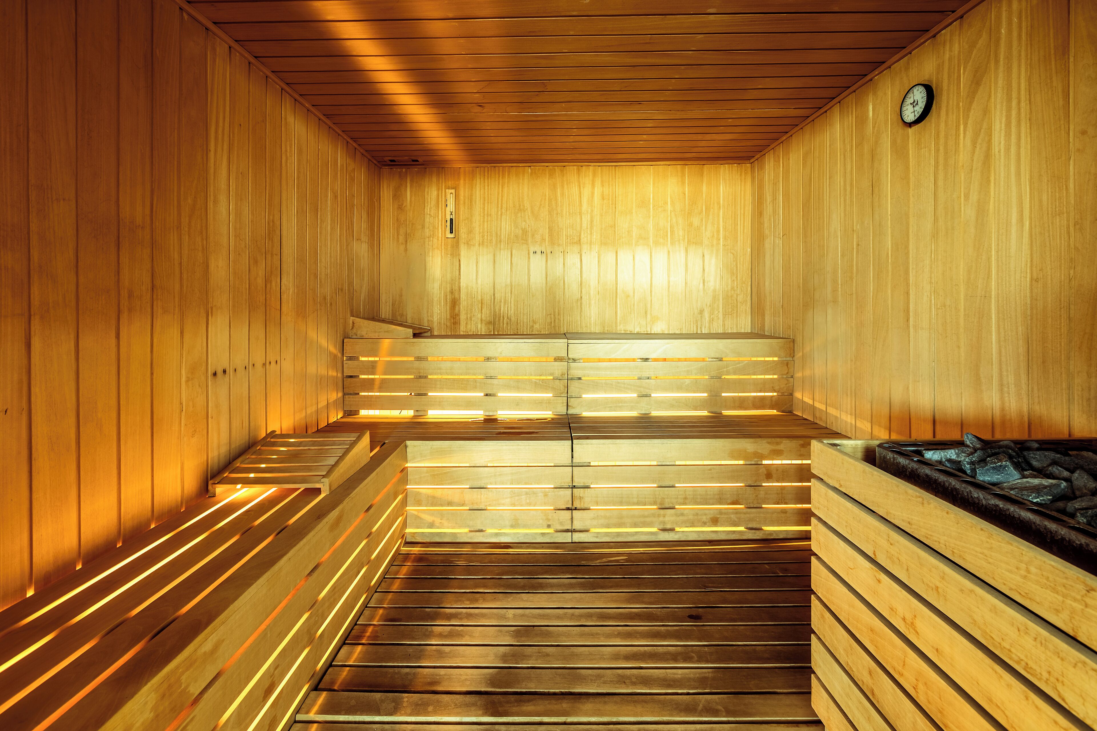 Een sauna met houten banken en een stenen wasbak.