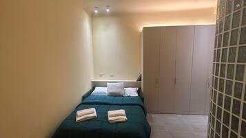 Ein kleines, aufgeräumtes Schlafzimmer mit Bett, Kleiderschrank und Nachttisch.