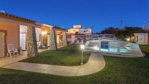 Une maison moderne dotée d’une piscine, de piliers en pierre et d’une pelouse bien entretenue.