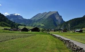En landlig landsby med traditionelle huse, en stenvæg og et bjerg i baggrunden.