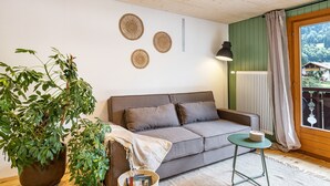 Una sala acogedora con un sofá, una mesita, una lámpara y una planta en maceta.