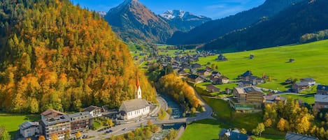 A mountain village with a church, a river, and houses.