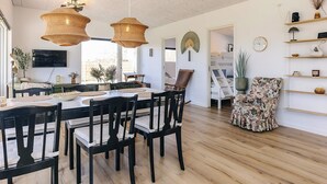 Un comedor con una mesa y sillas de madera, un televisor montado en la pared y un ventilador de techo.