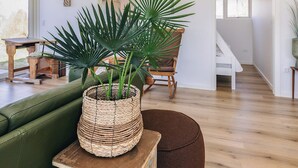 Una habitación con un sofá de cuero verde, una cesta de mimbre con una planta, una mesa de madera y una silla.